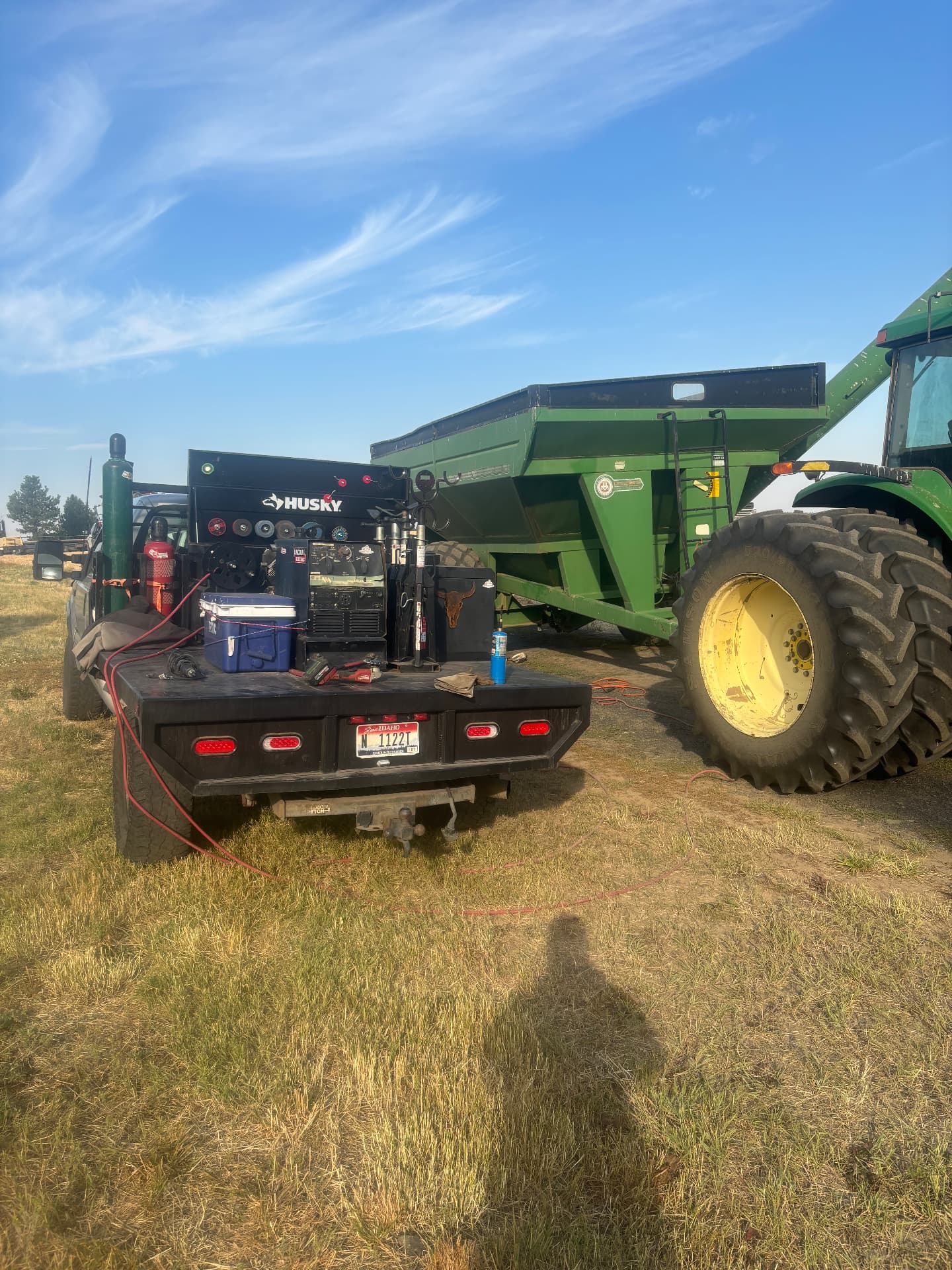 Kobar Welding mobile welding rig staged beside a grain cart and tractor in a farm field