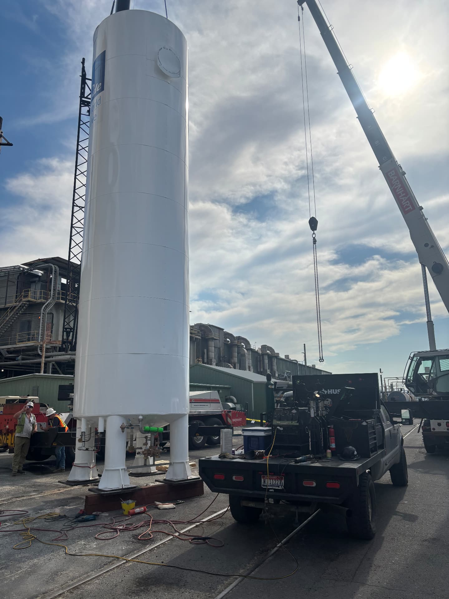 Kobar Welding mobile rig staged beside a tall industrial vessel being installed with a crane on a plant yard