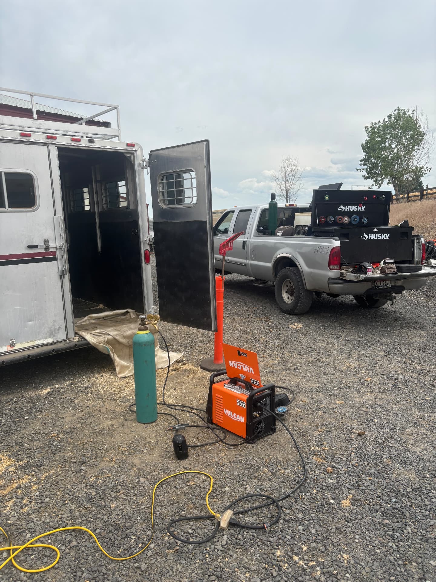 Mobile welding setup beside a horse trailer on site